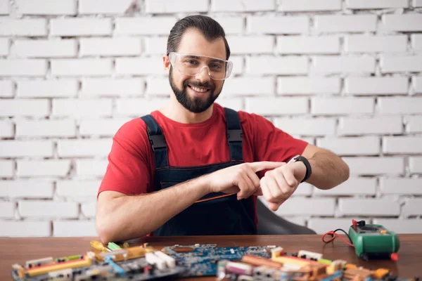 The technician on electronics repair poses on the camera with the details from the computer.