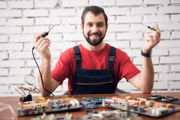 The technician on electronics repair poses on the camera with the details from the computer.