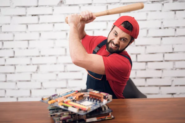 The master of electronics repair beats a baseball bat on computer parts. — Stock Photo, Image