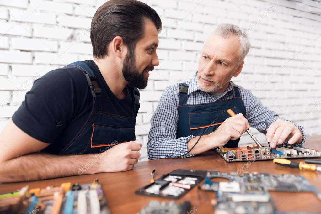 Adult and young men repair parts from the computer together.