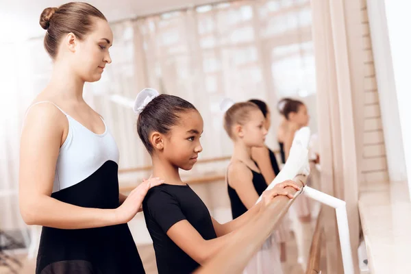 De trainer van de balletschool helpt jonge ballerina's voeren verschillende choreografische oefeningen. — Stockfoto