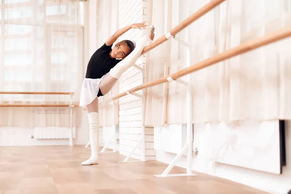 The girl is training a stretch of her legs near the ballet barr. — Stock Photo, Image