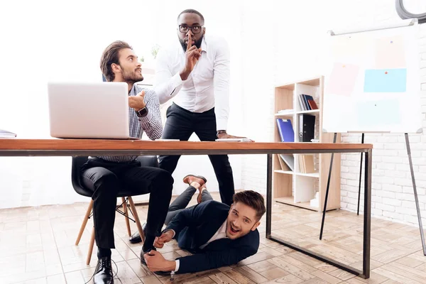 Человек под столом, чтобы завязать шнурки своему коллеге по бизнесу . — стоковое фото