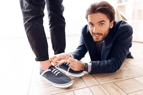 Человек под столом, чтобы завязать шнурки своему коллеге по бизнесу . — стоковое фото
