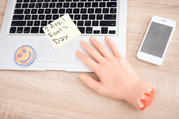 On the table lies a fake hand near the laptop and a smiley face. — Stock Photo, Image