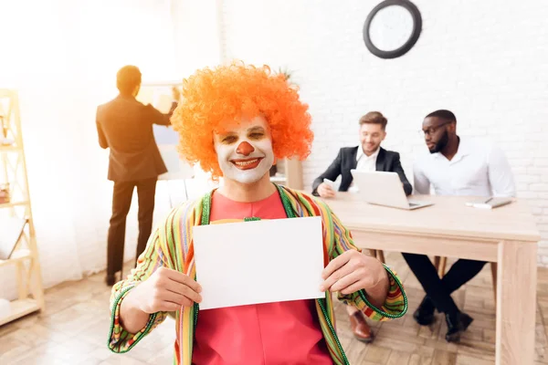 Człowiek w garniturze clown i perukę siedzi w biurze firmy na 1 kwietnia. — Zdjęcie stockowe
