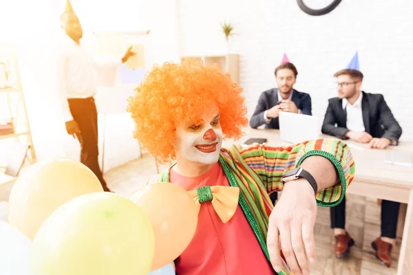 Человек в костюме клоуна и парике сидит в офисе 1 апреля . — стоковое фото
