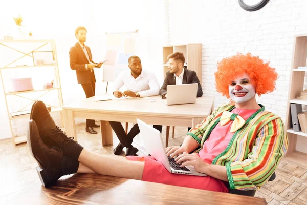 A man in a clown suit sitting at his desk, his feet up on the table. — Stock Photo, Image
