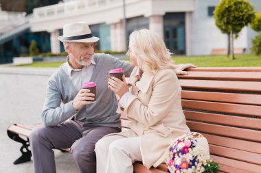 İki emekliler ile bir bardak kahve ellerinde bir bankta oturuyor. Birbirinize hassasiyet ile bakın
