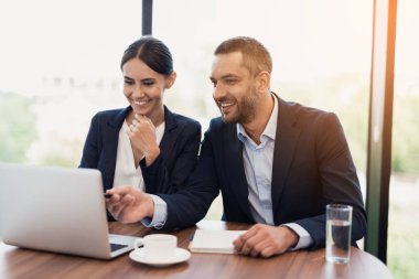 Bir erkek ve bir kadın sıkı iş takım elbiseli bir şey bir fincan kahve ile bir masada otururken görüşüyorlar