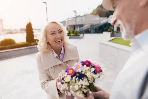 Un anciano presentó un hermoso ramo de flores a una mujer. Tienen una cita. — Foto de Stock