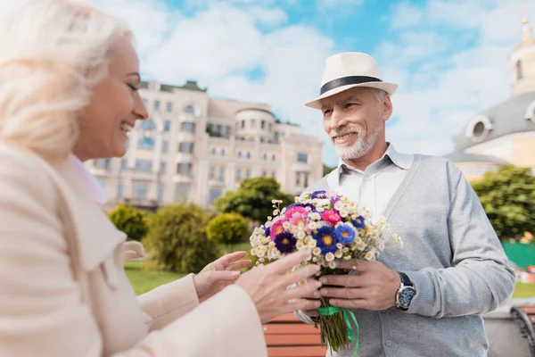 初老の男性は、女性に花の美しい花束を提示しました。日付を持っています。 — ストック写真