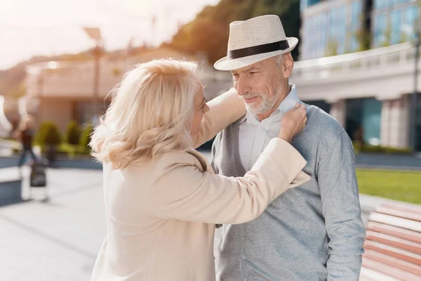 Una pareja de ancianos se conocieron en la calle. Mujer endereza el cuello del hombre — Foto de Stock