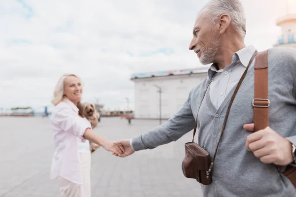 Una pareja de ancianos está caminando por la plaza. Una mujer coge a un hombre de la mano y lleva — Foto de Stock