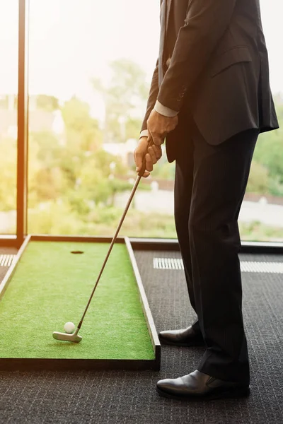 Chiudete. Un uomo in abito da lavoro gioca a golf in ufficio — Foto Stock