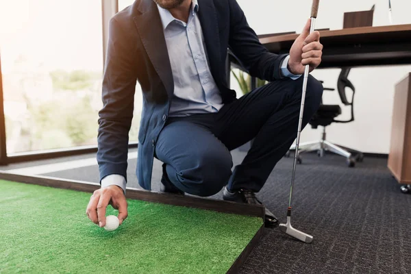 Fecha. Um homem de fato de negócios joga golfe no escritório — Fotografia de Stock