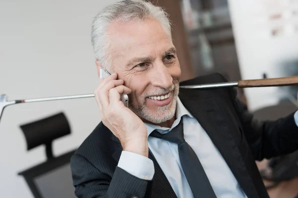 A respectable man sits on the edge of the table in his office and talks on the phone — Stock Photo, Image