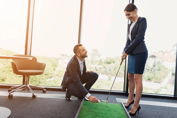 Egy ember teszi egy golf labdát egy üzleti hölgy előtt szigorú öltönyt. Egy nő, egy csapásra készül — Stock Fotó