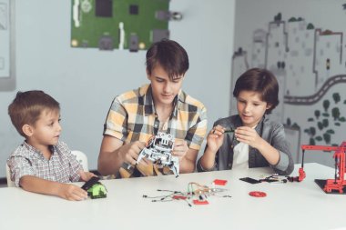 Genç bir adam iki erkek bir robot montajı gösterilmiştir. Onlar gözlemlemek ve ilgi ile yardım