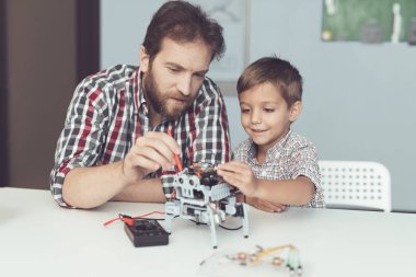 Adam ve küçük çocuk robotun performansını ölçmek. Bir dijital multimetre kullandıkları