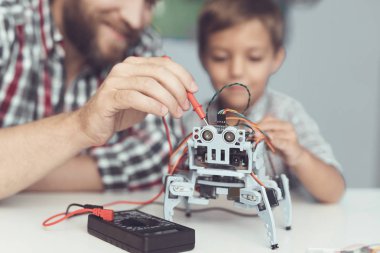 Adam ve küçük çocuk robotun performansını ölçmek. Bir dijital multimetre kullandıkları