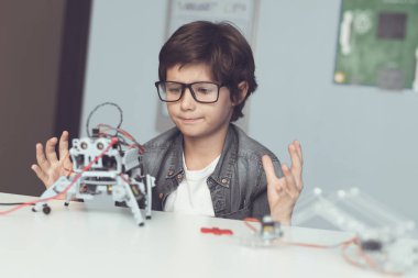 Gözlüklü küçük inek bir robot tutuyor. O heyecanla onun oluşturma sırasında görünüyor