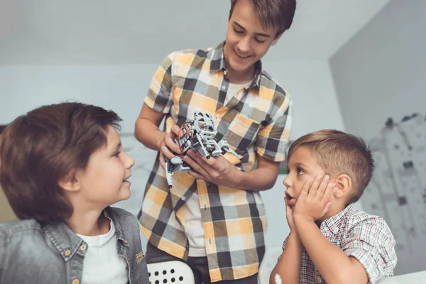 Den unga killen förde två pojkar en grå robot. Barn är entusiastiska över robot — Stockfoto