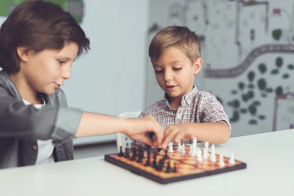 Två pojkar spela schack som sitter vid ett bord och är uttråkad. — Stockfoto