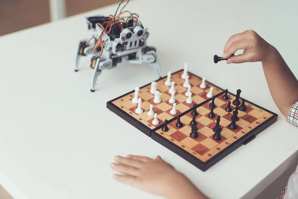 En liten pojke spelar schack med en grå robot. Robot spelar för vita — Stockfoto