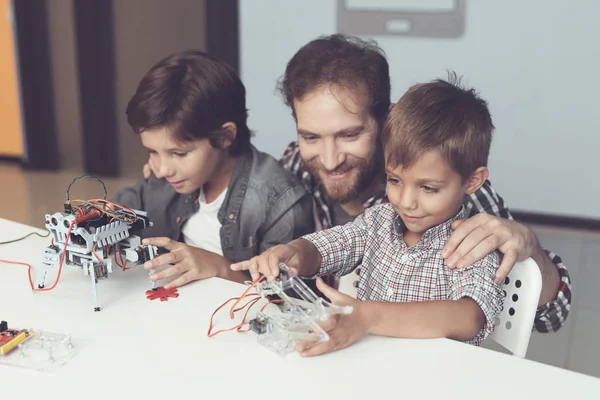 Bir adam ve iki erkek bir robot inşa. Adam çocuklar derleme ile yardımcı olur — Stok fotoğraf