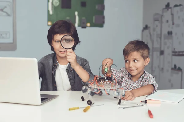 Am Tisch sitzen zwei Jungen. Einer von ihnen sitzt vor einem grauen Laptop. Sie arbeiten am Tisch — Stockfoto