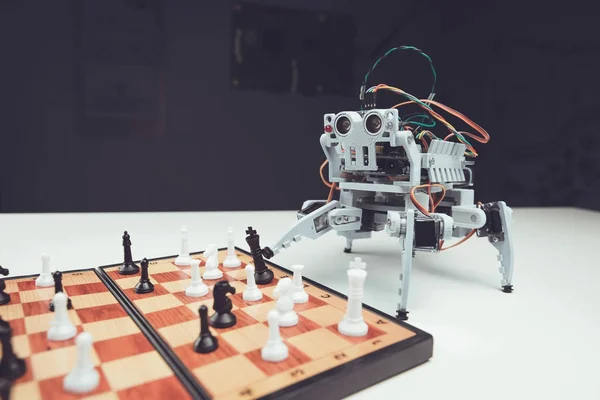 ロボットをクローズ アップ。小さな灰色のロボットはチェス盤の横にあるテーブルの上 — ストック写真