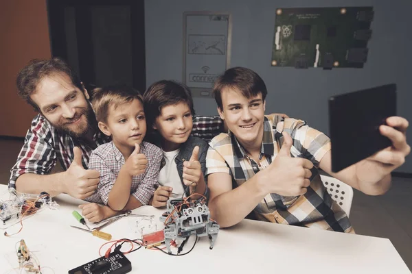 Twee jongens een tiener en een volwassen man doen selfie op een zwarte tablet. Ze ontwerpen robots — Stockfoto