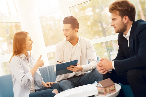 Junges Paar bei einem Treffen mit einem Makler. Mann und Frau schließen Vertrag mit Immobilienmakler. — Stockfoto