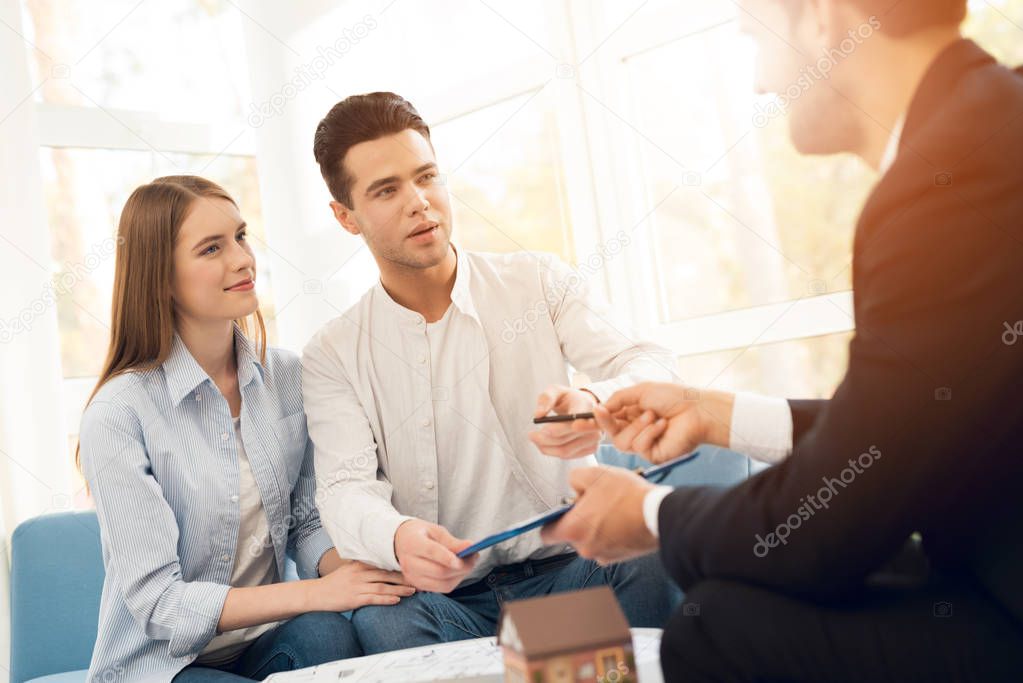 Young couple in a meeting with a realtor. Guy and girl make a contract with realtor buying property.