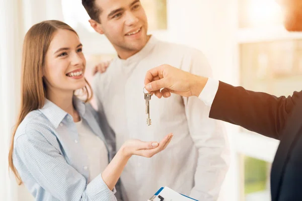 Pareja joven en una reunión con un agente inmobiliario. Guy y chica hacen un contrato con un agente inmobiliario comprando una propiedad . — Foto de Stock