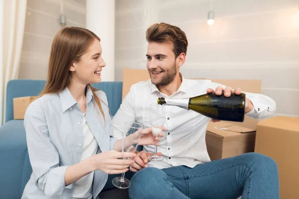 Ungt par firar med champagne flyttar till ny lägenhet. Flytta nygifta till nya bostäder. — Stockfoto