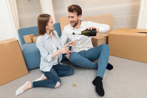 Giovane coppia che festeggia con champagne trasferirsi in un nuovo appartamento. Trasferire gli sposi in un nuovo alloggio . — Foto Stock
