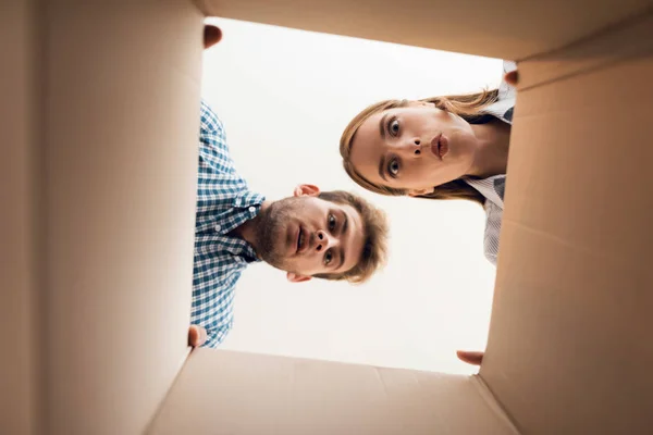 A rapariga e o rapaz estão a olhar para a caixa vazia. Vista de dentro da caixa close-up . — Fotografia de Stock