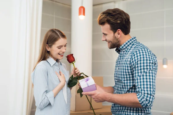 Guy gives his girlfriend a rose and gift. Girl is very happy with the gifts from the guy. — Stock Photo, Image