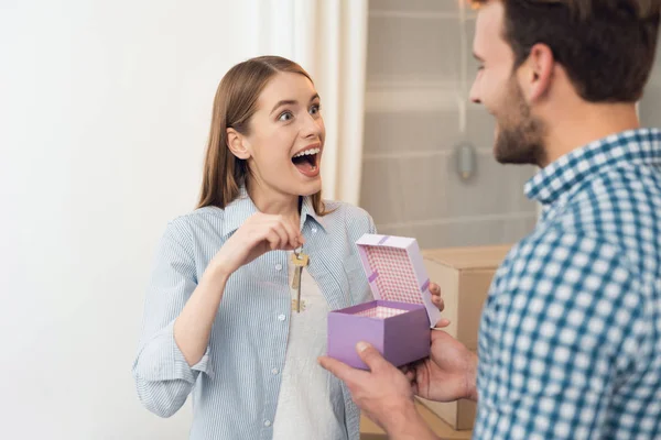 Der Kerl schenkt seinem Mädchen eine Schachtel mit einem Geschenk. das Mädchen erhielt ein Geschenk, den Schlüssel für eine neue Wohnung. — Stockfoto