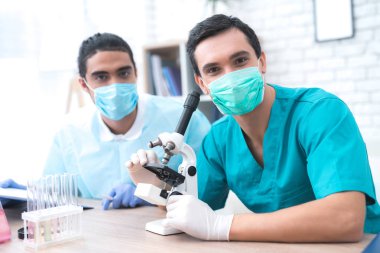 İki doktor mikroskopla masadan kamera poz.