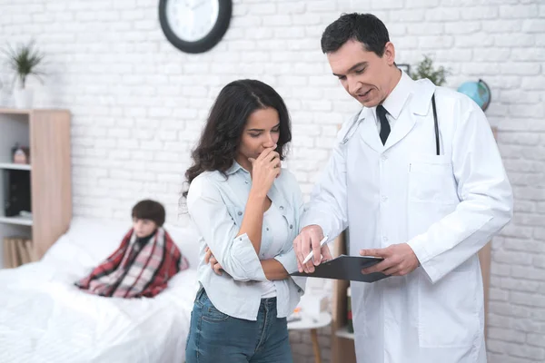 La joven madre habla con el médico que llegó a casa con el niño enfermo . — Foto de Stock