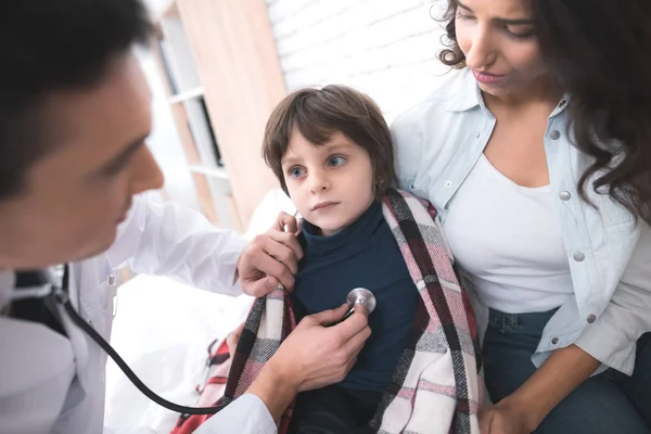 Il medico ascolta i polmoni di un ragazzo malato in uno stetoscopio . — Foto Stock