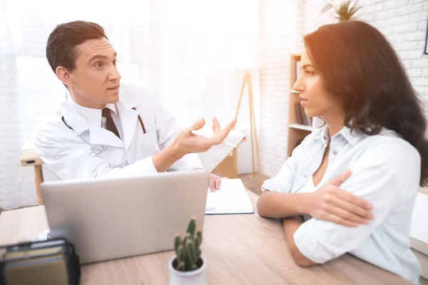 Una joven madre está hablando con un médico en el consultorio de su médico. . — Foto de Stock