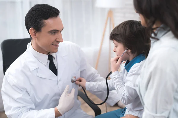 El médico le da al niño que escuche el estetoscopio. . — Foto de Stock