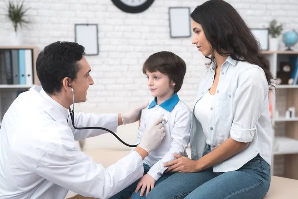 El médico escucha los pulmones de un niño enfermo en un estetoscopio . — Foto de Stock