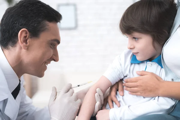 The doctor is preparing to make a prick to the sick boy.