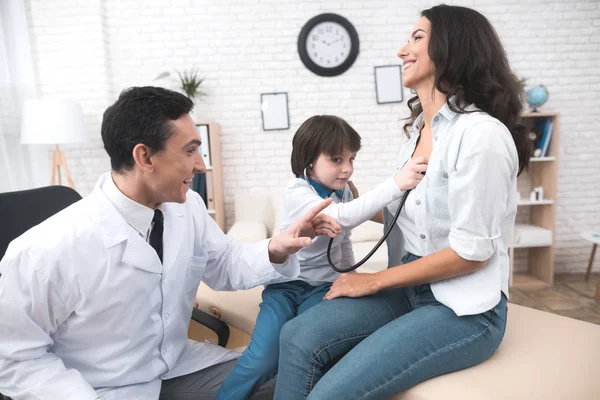 El médico le da al niño que escuche el estetoscopio. . —  Fotos de Stock