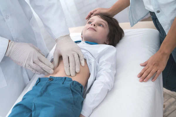 Le médecin en gants blancs masse le ventre d'un garçon malade . — Photo